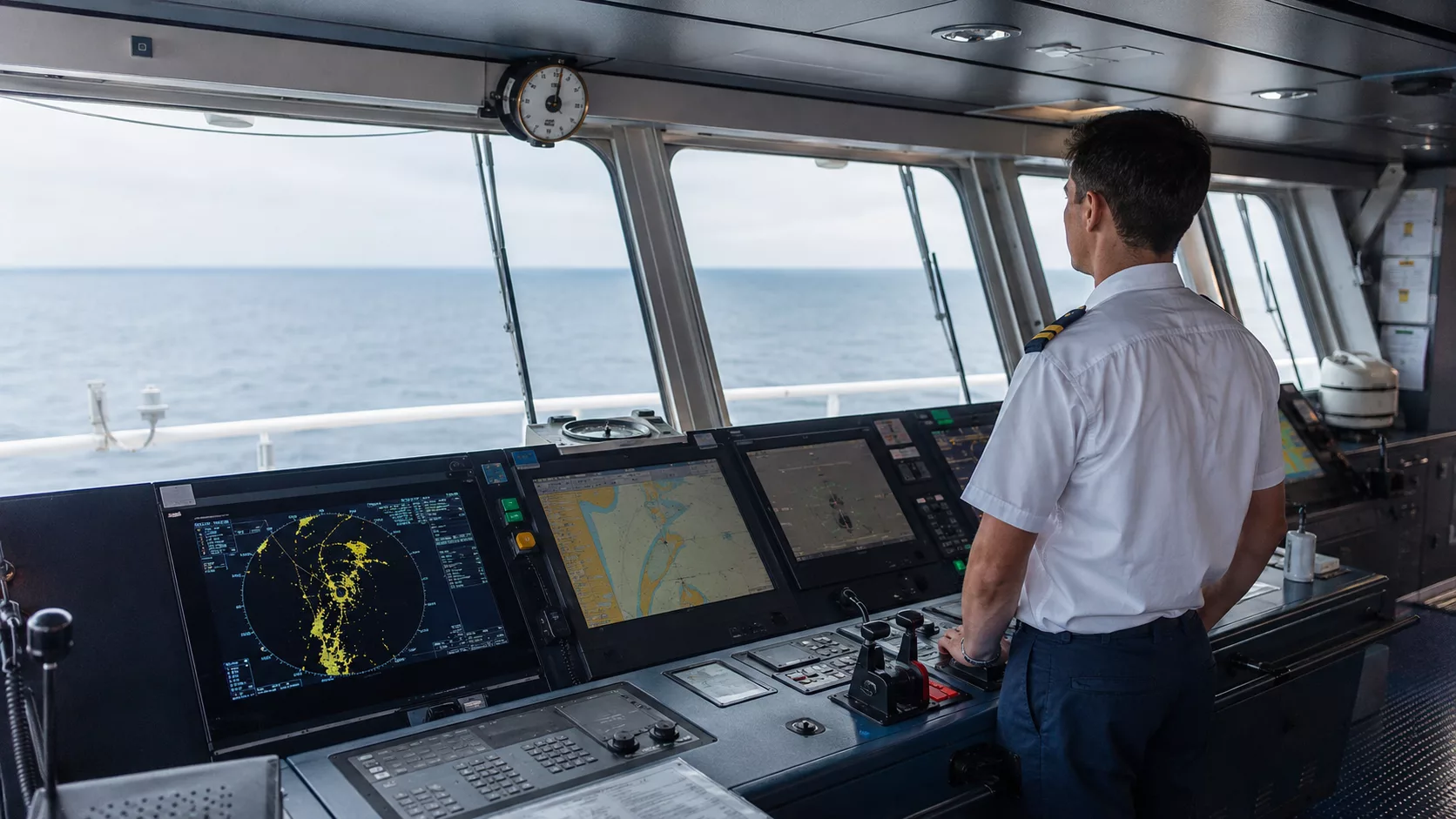 Gemi seyir aletleri kullanılan köprüüstünde radar, ECDIS, AIS ve gyro pusula ekranlarını inceleyen zabit adayı.