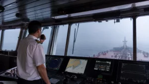 Gemi siren kodları ve düdük işaretlerini öğrenen denizcilik öğrencileri köprüüstünde sisli havada COLREG ses işaretlerini inceliyor.